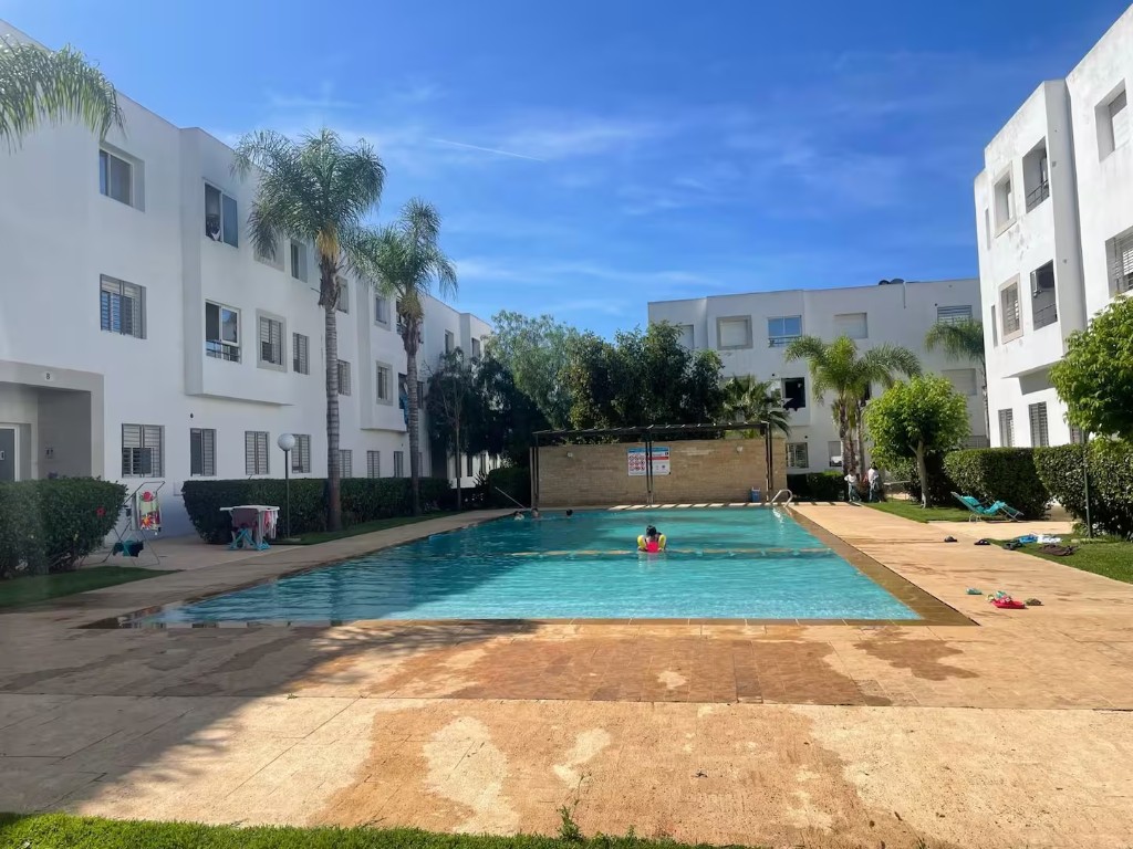 Piscine de la résidence avec palmiers et transats à Skhirat